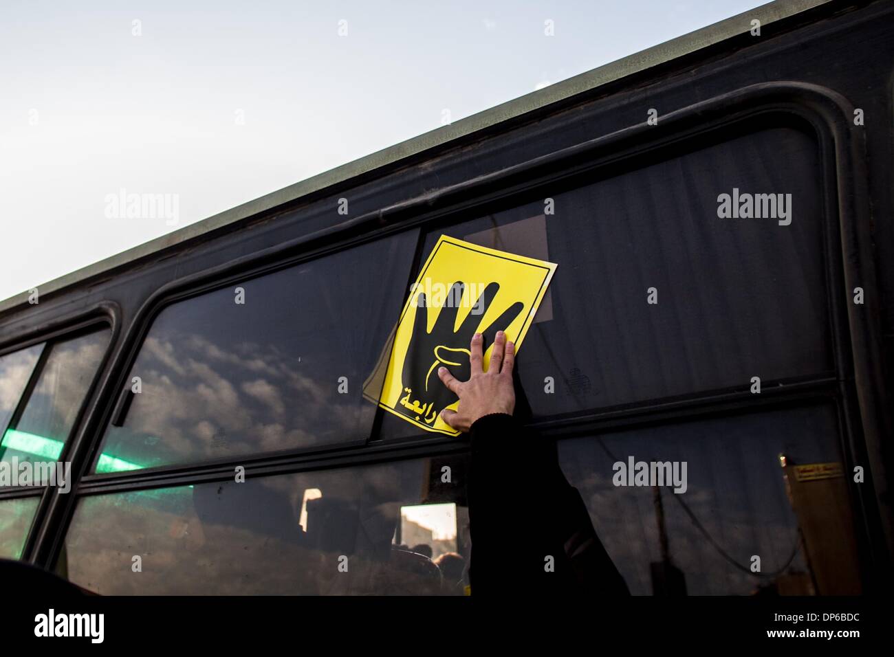 Kairo, Ägypten. 8. Januar 2014. Ein Demonstrant legt einen Aufkleber auf einem Busfenster während eines Marsches in Nasr City, Ägypten, 8. Januar 2014. Kairo Strafgerichtshof vertagte am Mittwoch den Spuren des gestürzten Präsidenten Mohamed Morsi über Anstiftung die Tötung von Demonstranten zum 1. Februar wegen des schlechten Wetters, die seinen Transport des Gerichts verhindert das Staatsfernsehen berichtet. Bildnachweis: Amru Salahuddien/Xinhua/Alamy Live-Nachrichten Stockfoto