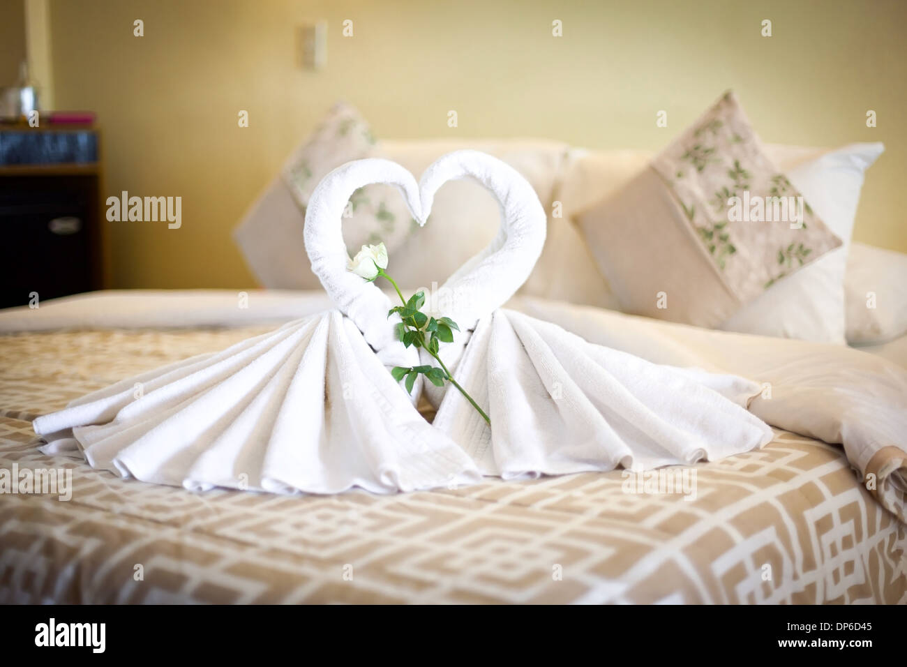 Zwei weißen Handtüchern Schwäne auf Bettlaken, dekorierte Rose und Herz in Hotelzimmer Stockfoto