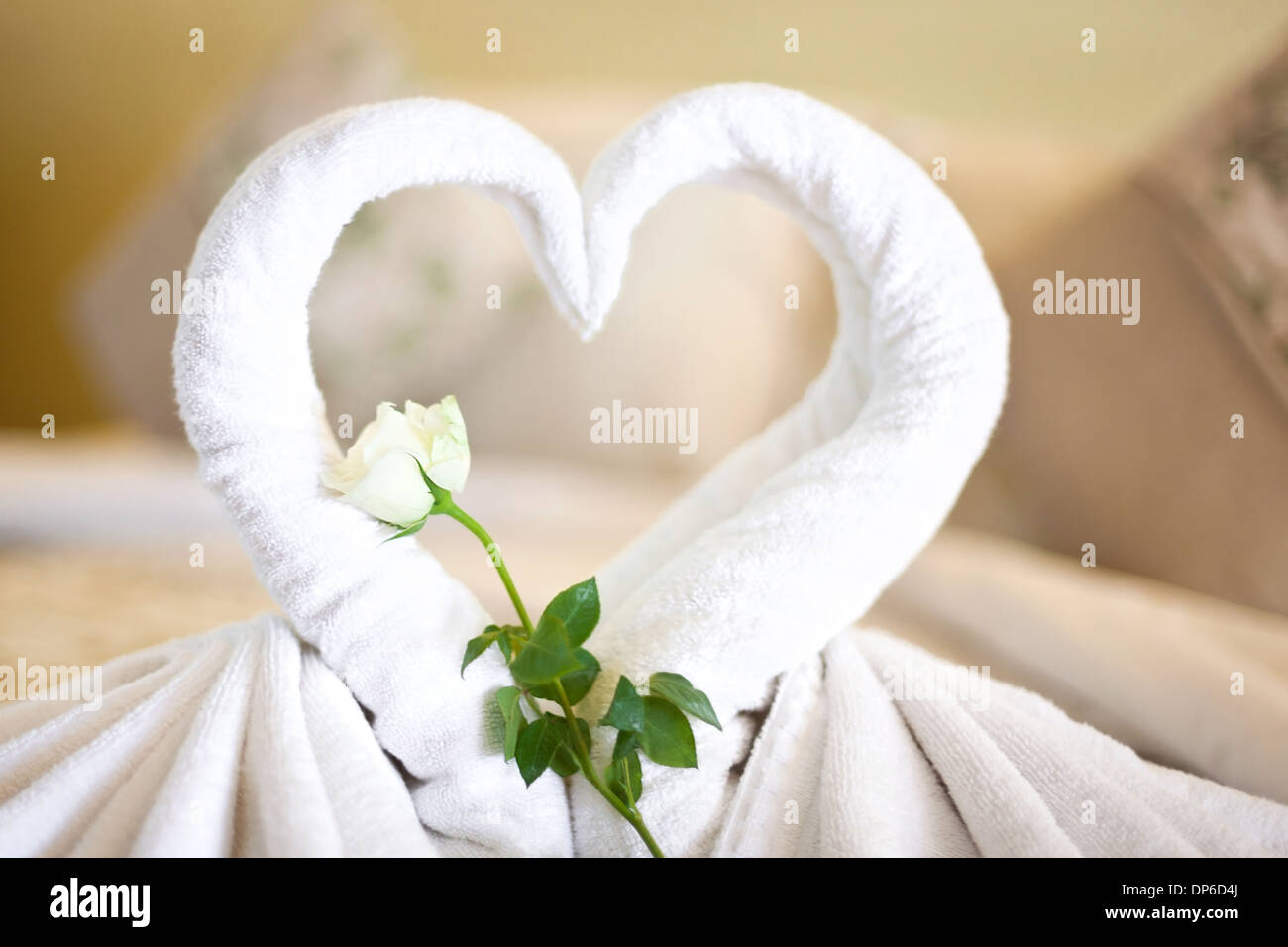 Zwei weißen Handtüchern Schwäne auf Bettlaken, dekorierte Rose und Herz in Hotelzimmer Stockfoto