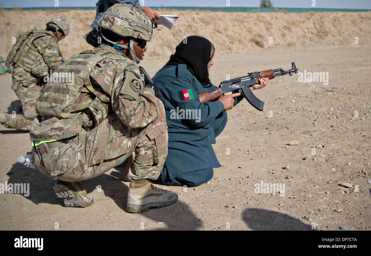 Eine weibliche US Army Soldat Züge einer afghanischen Nationalpolizei rekrutieren tragen Kopfbedeckung in Brand ein AK-47 in Qualifikation am Joint Afghan National Police Regionalzentrum 7. Dezember 2013 in Kandahar, Afghanistan. Stockfoto