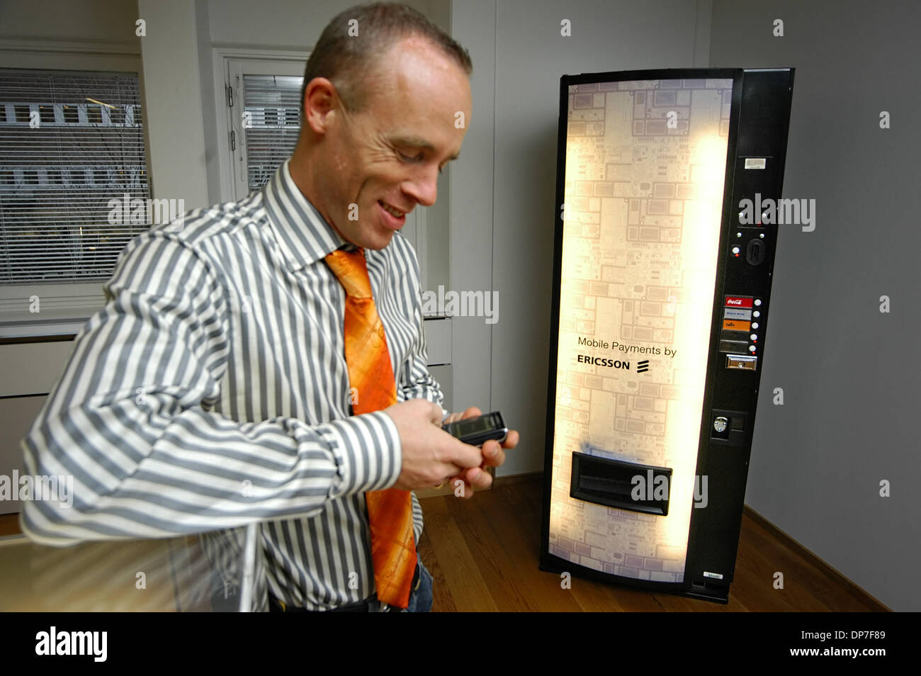 14. November 2006; Kista, Schweden; Ein Rundgang durch die Ericsson-Welt-Hauptquartier in Kista. Im Bild, kauft Führungskraft Ericsson eine Dose Cola aus einem Automaten in der Lobby. Die Getränke sind frei und am Automaten gibt es einen neuen Weg zu zeigen, die Benutzung von Mobiltelefonen Produkte verkauft werden können. In diesem Fall der Käufer schickt eine einfache Textnachricht, Out knallt die Soda und der Schal Stockfoto