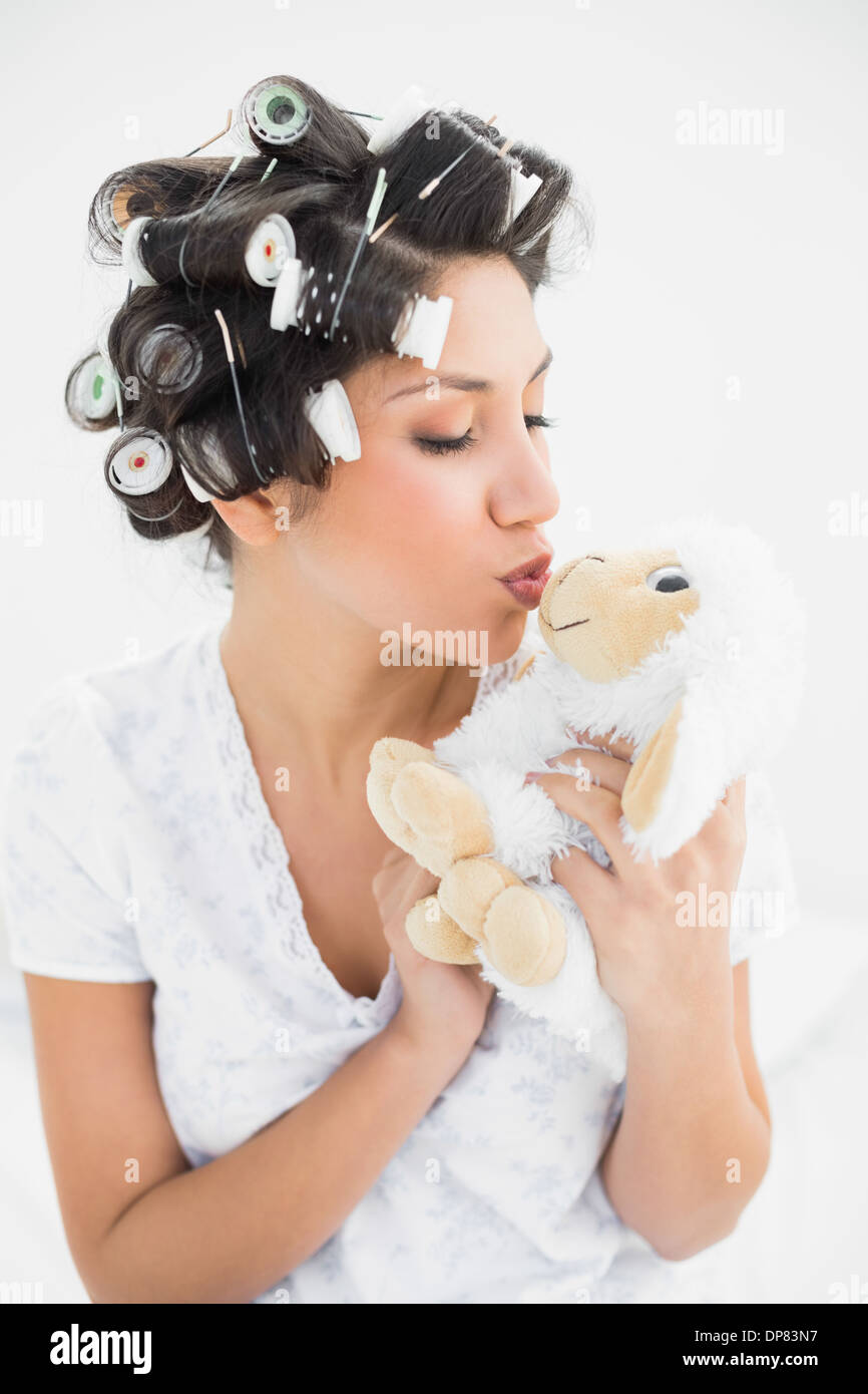 Brünette in Lockenwickler küssen Schafe Teddy Stockfoto