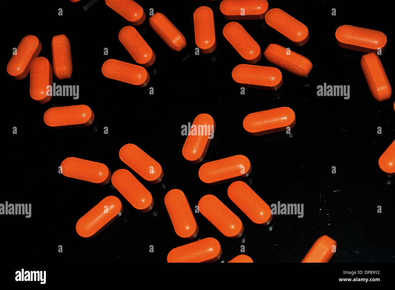 Ein schwarzer Teller bedeckt in hellen orange Pillen. Stockfoto