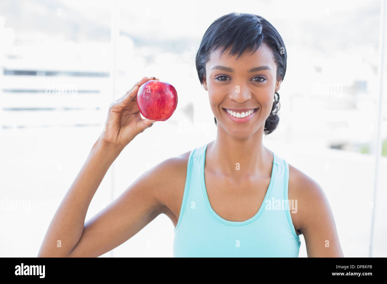 Erfreut schwarze behaarte Frau hält einen Apfel Stockfoto