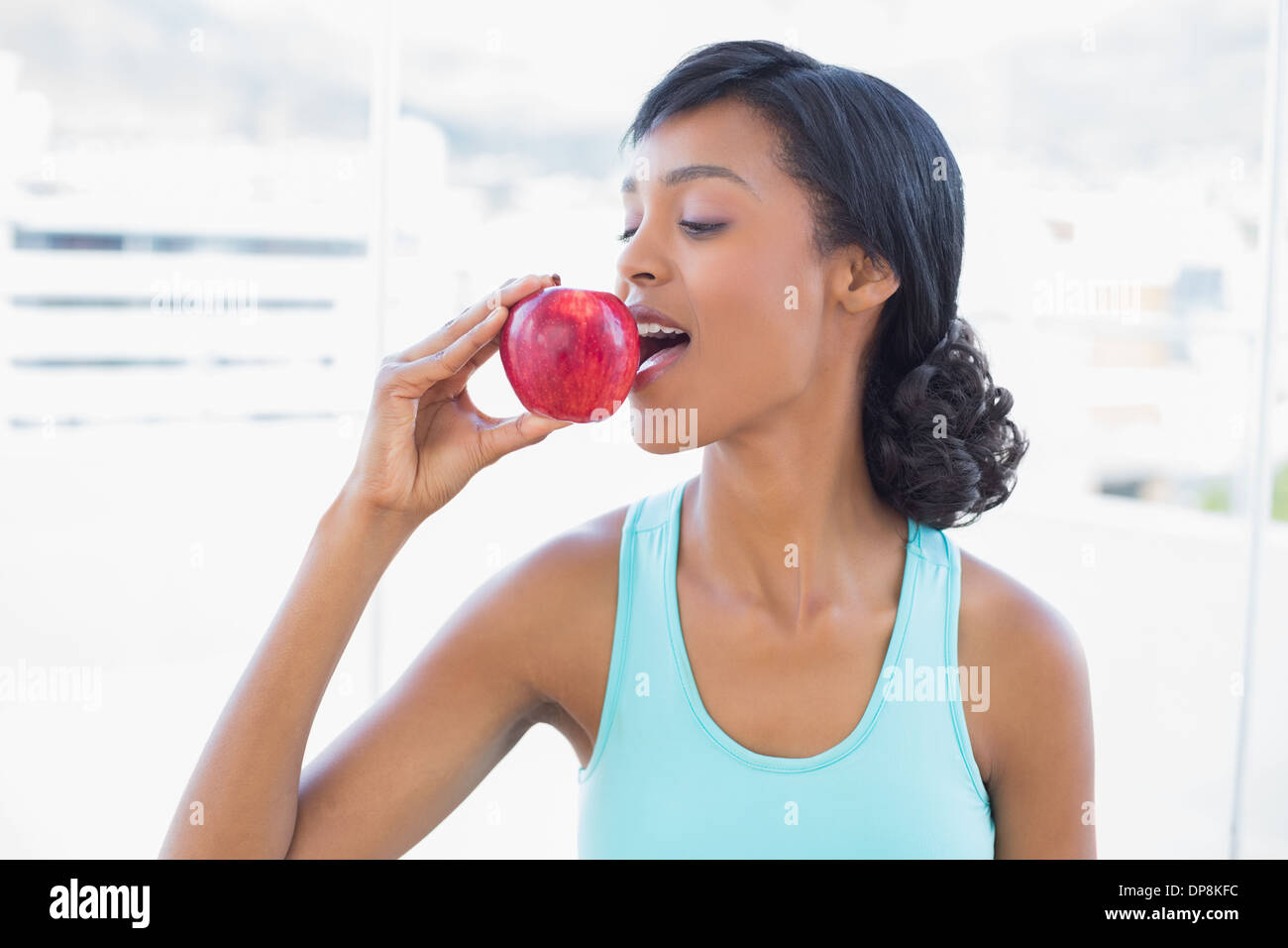 Schöne schwarze behaarte Frau einen Apfel essen Stockfoto