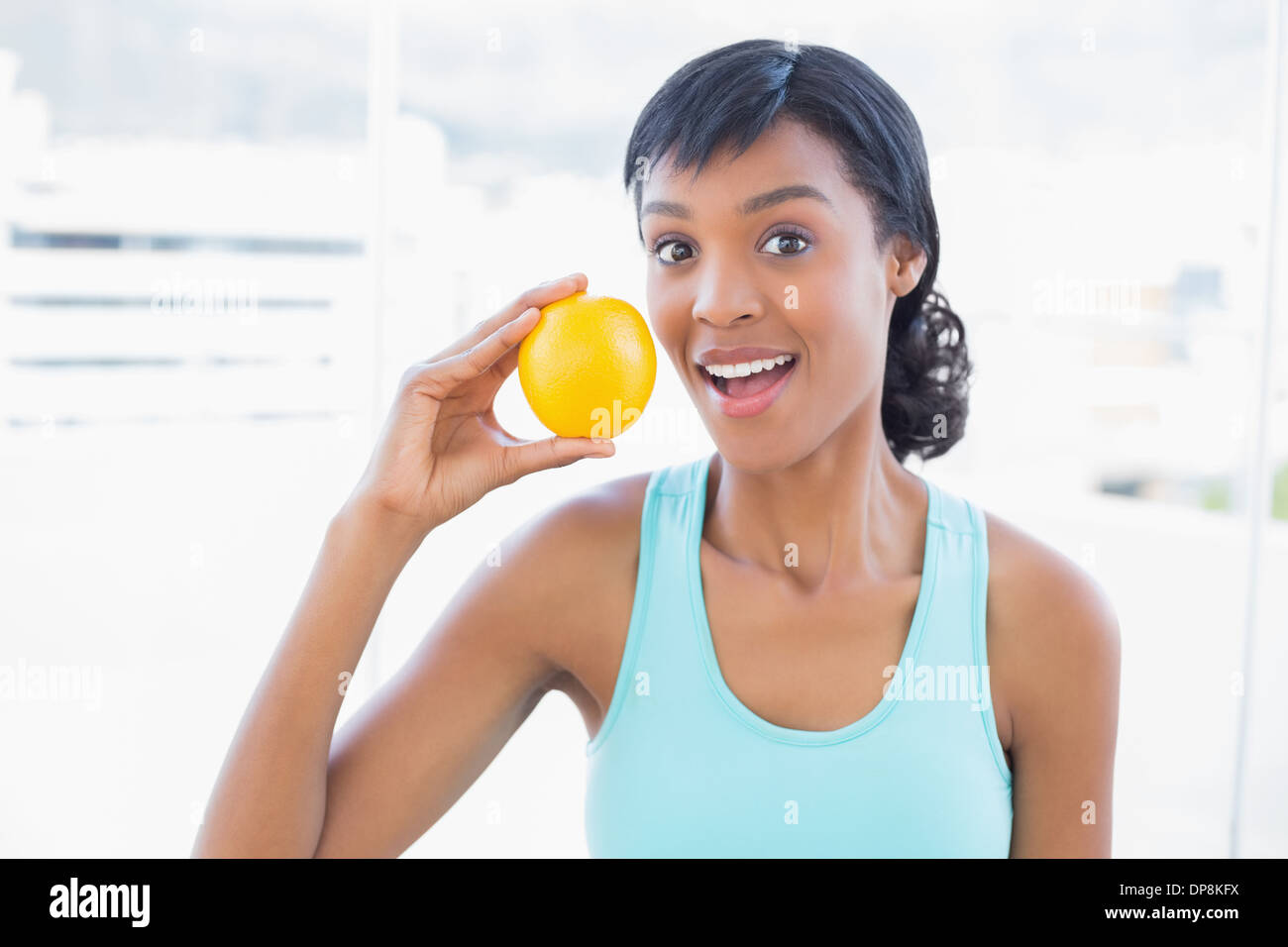 Überrascht schwarz behaarte Frau hält eine orange Stockfoto