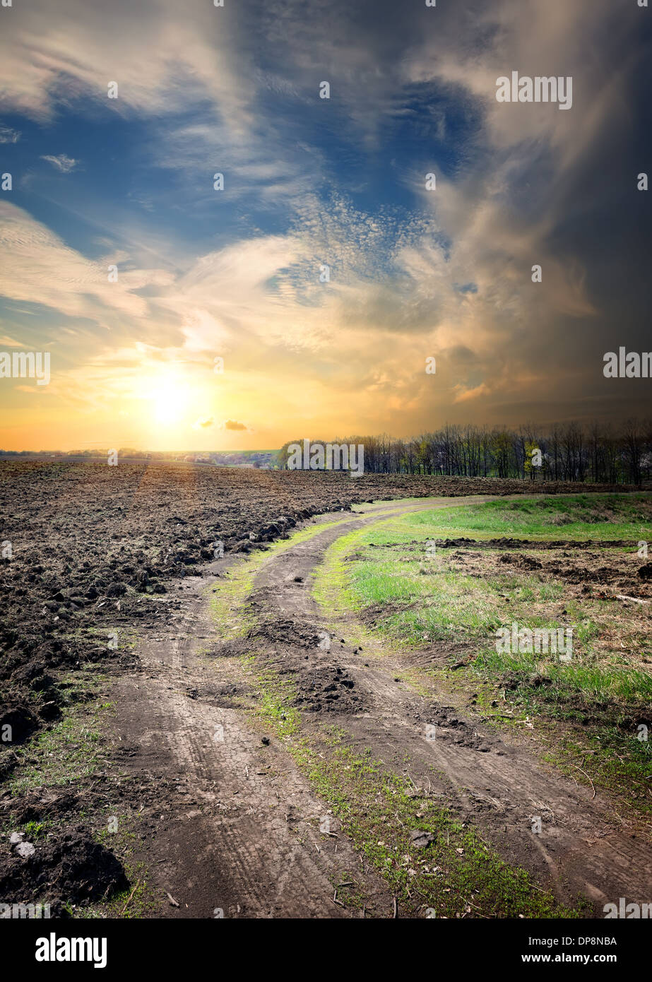Sonnenuntergang und Land Straße durch gepflügtes Feld Stockfoto