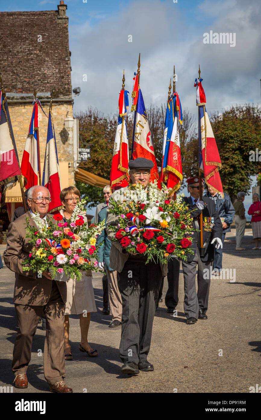 Place De La Halle, Domme, Dordogne, Frankreich, Europa. Parade der Kriegsveteranen sammeln vor dem Tourist Office-Gebäude. Stockfoto