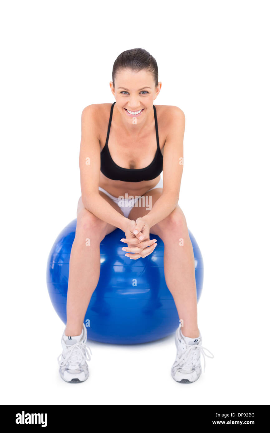 Lächelnde Frau in Sportbekleidung auf Gymnastikball sitzen passen Stockfoto