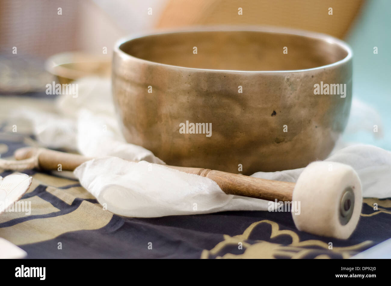 Eine schöne Hand geschlagen, tibetische Klangschale mit Taktstock Plaed auf einen weißen Schal buddhistischen. Stockfoto