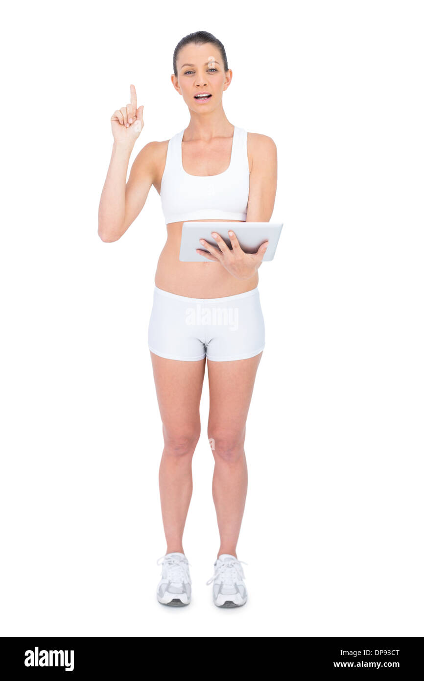 Fit Woman Sportswear Tablet halten und nach oben Stockfoto