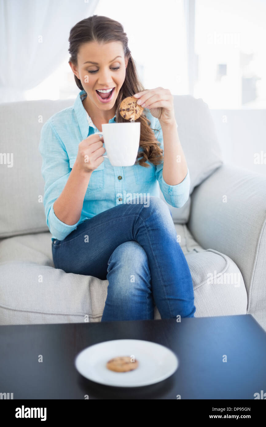 Glückliche Frau dunking Keks in heiße Schokolade Stockfoto