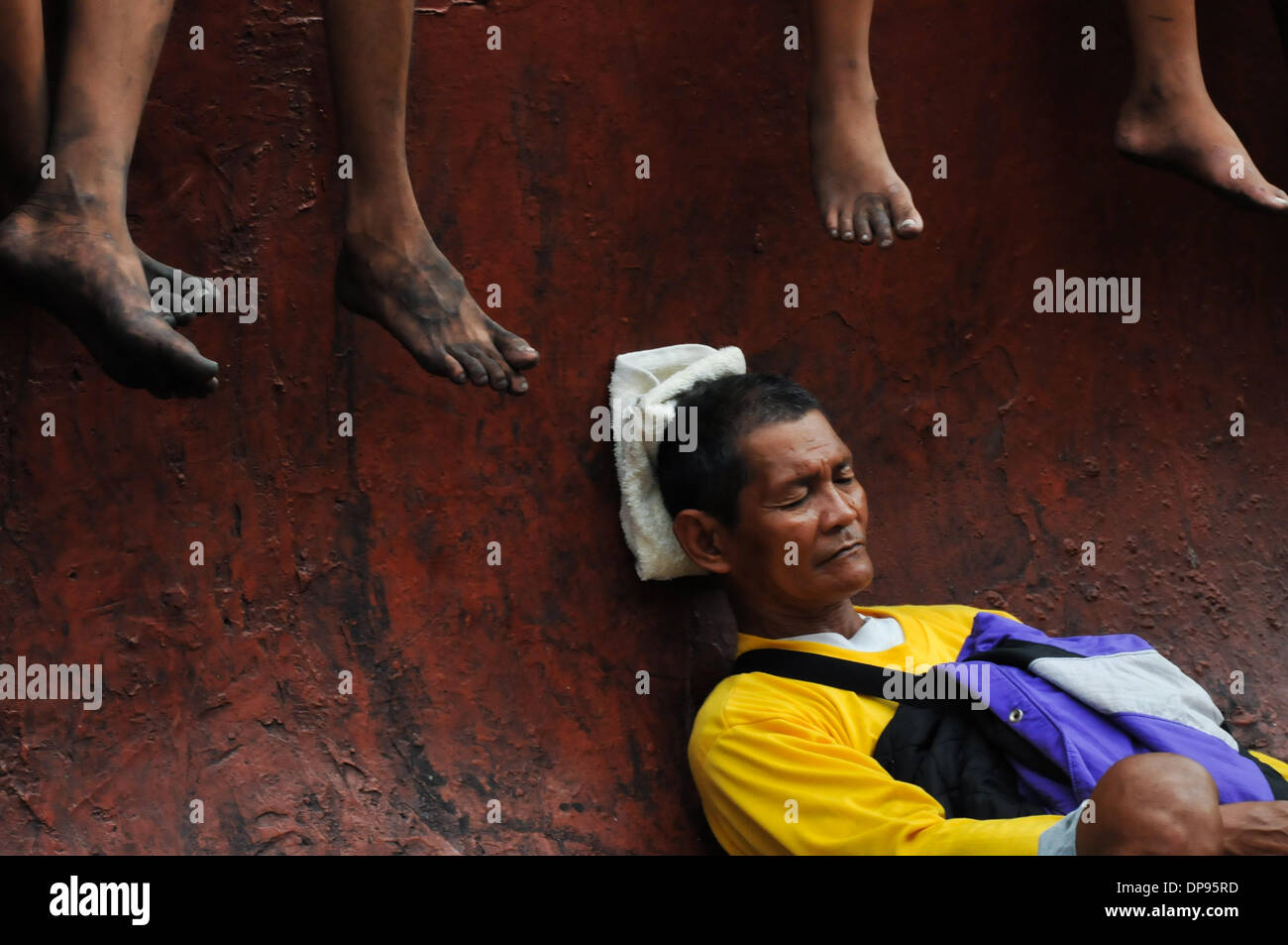 Manila, Philippinen. 9. Januar 2014. MANILA, Philippinen - ruht ein Mann seine Augen, als er auf dem Bürgersteig sitzt, wie katholische philippinische Anhänger Teil an der jährlichen '' Traslacion'', spanische Bezeichnung für Bewegung oder eine Passage, während das Fest des schwarzen Nazareners in Manila nehmen. Die Black Nazarene ist ein Jahrhunderte altes Bild von Jesus Christus sein Kreuz zu tragen und wird weit geglaubt, um Wunder zu vollbringen. WS-Credit: ZUMA Press, Inc./Alamy Live News Stockfoto