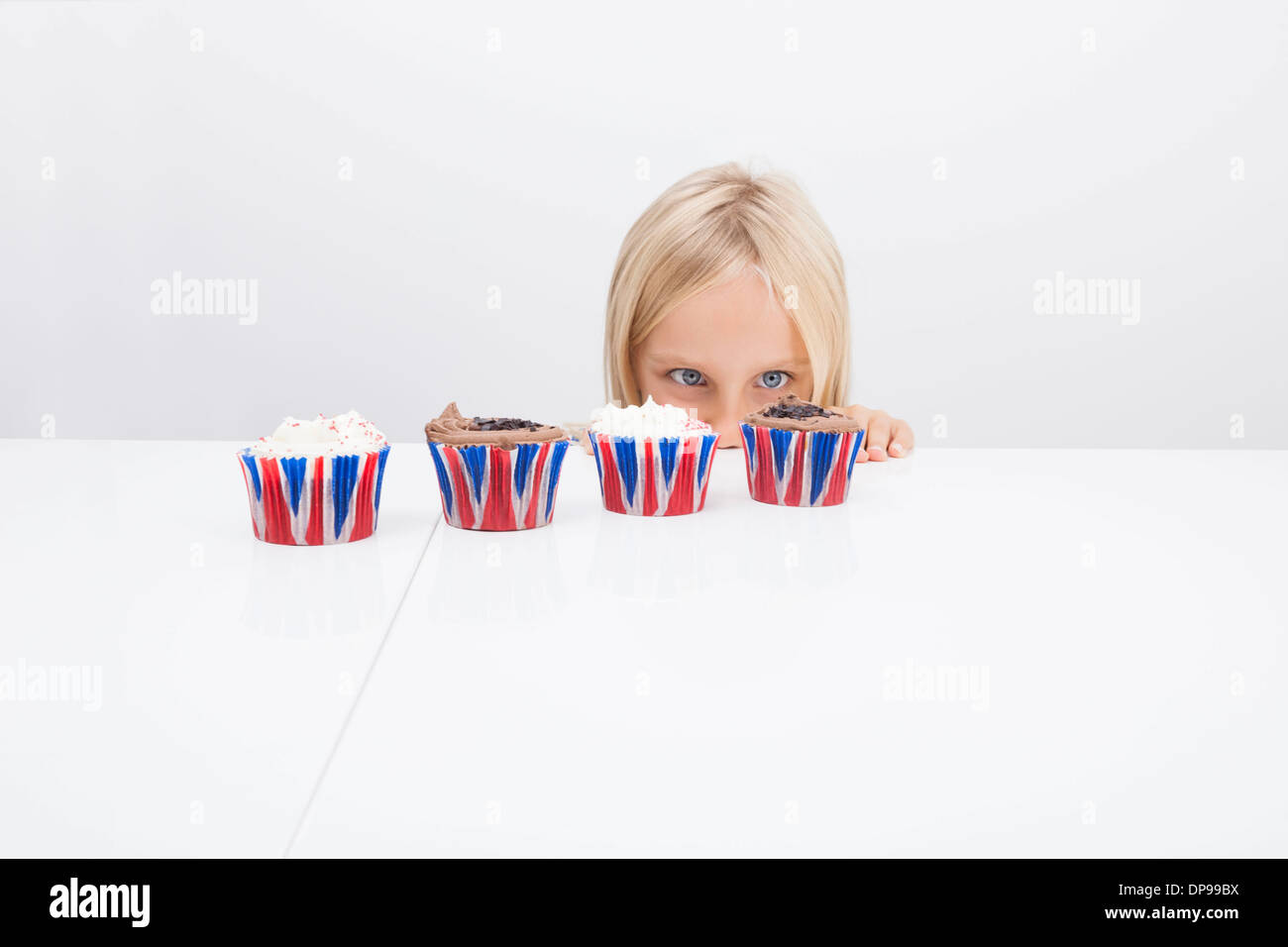 Mädchen starrte auf Cupcakes auf Tisch Stockfoto