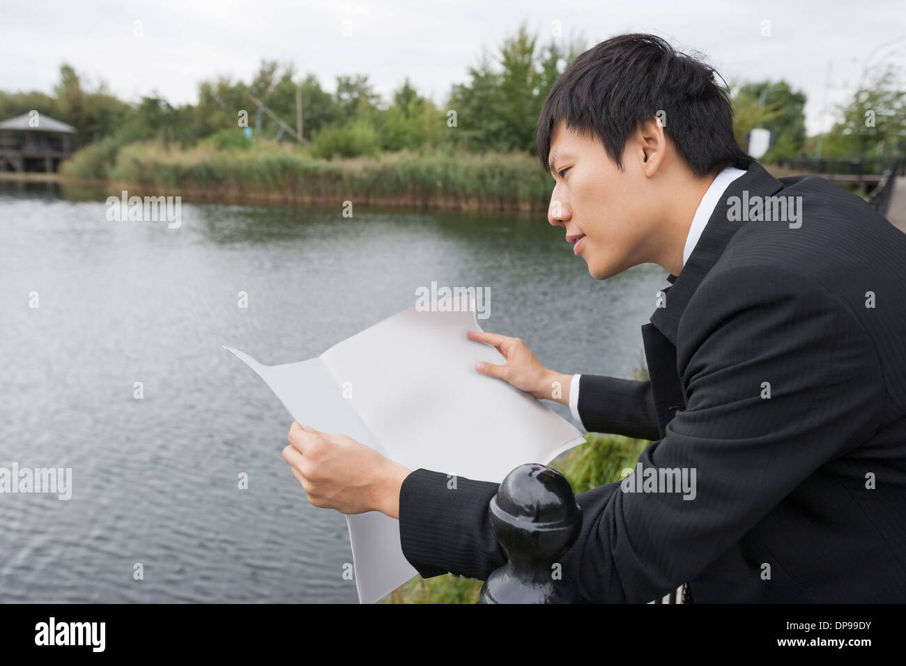 Seitenansicht des asiatischen Geschäftsmann lesen Zeitung außerhalb Stockfoto
