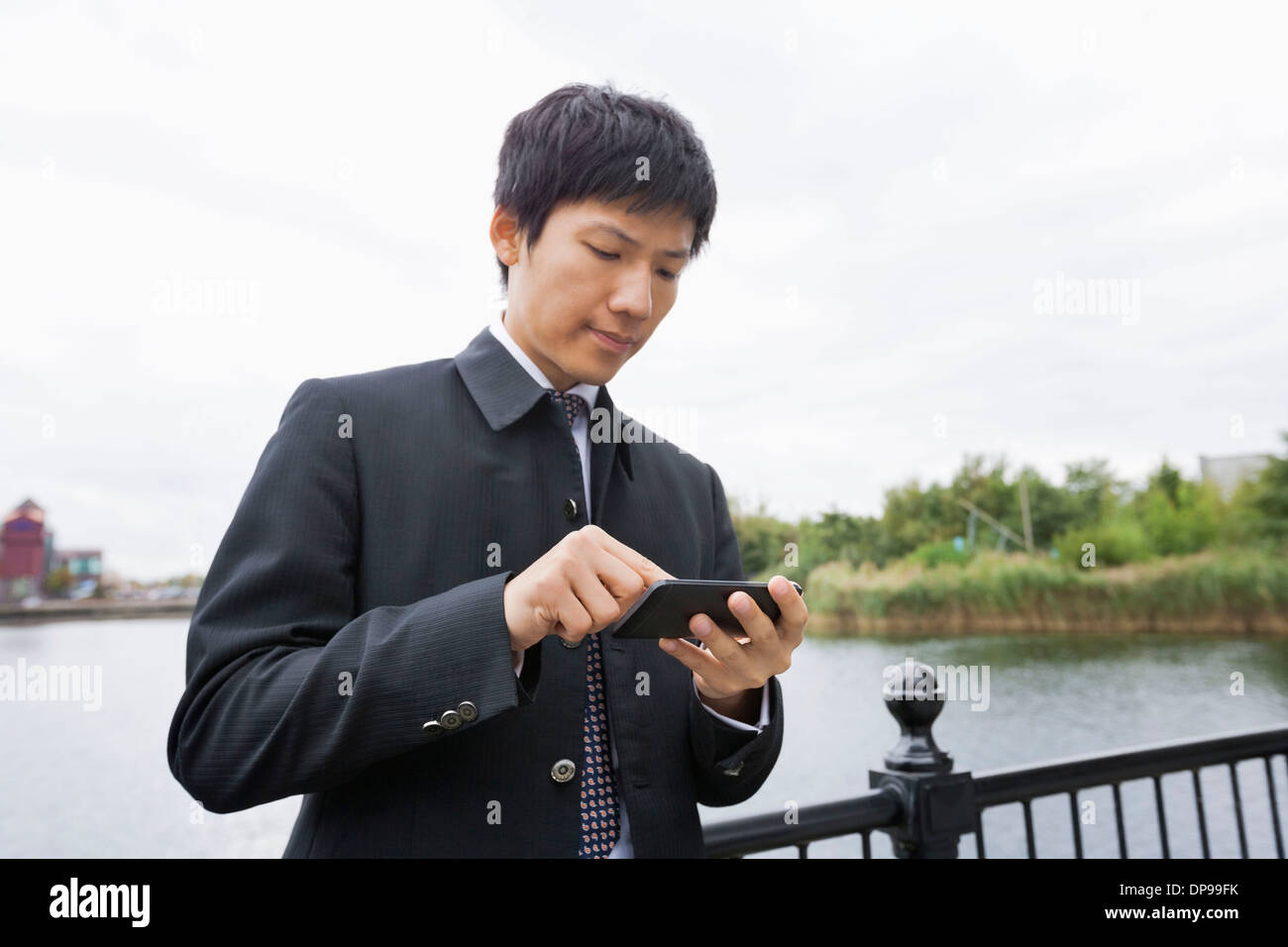 Mitte adult asiatischen Geschäftsmann mit Handy-Fluss entlang Stockfoto