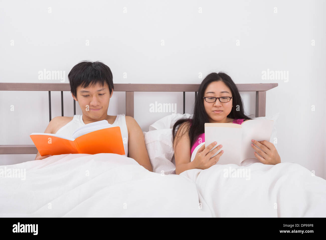 Asian paar lesen Bücher im Bett Stockfoto