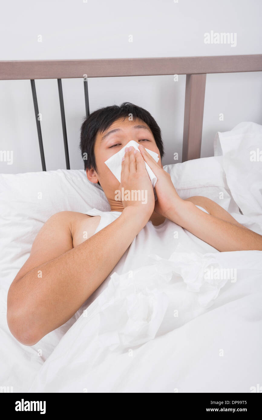 Asiatischer Mann Nase weht im Bett Stockfoto