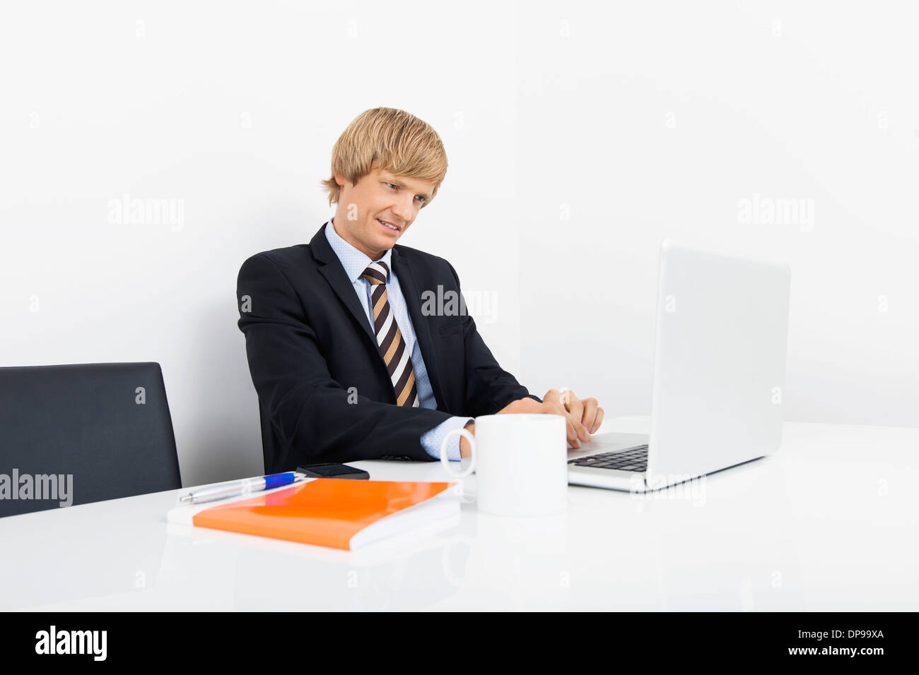 Zuversichtlich Geschäftsmann mit Laptop am Schreibtisch im laptop Stockfoto