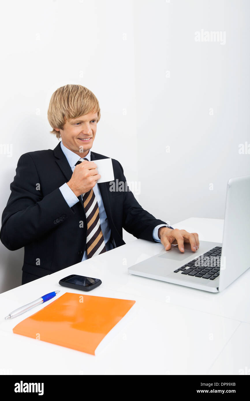 Zuversichtlich Geschäftsmann Kaffeetrinken weiß mit Laptop im Büro Stockfoto