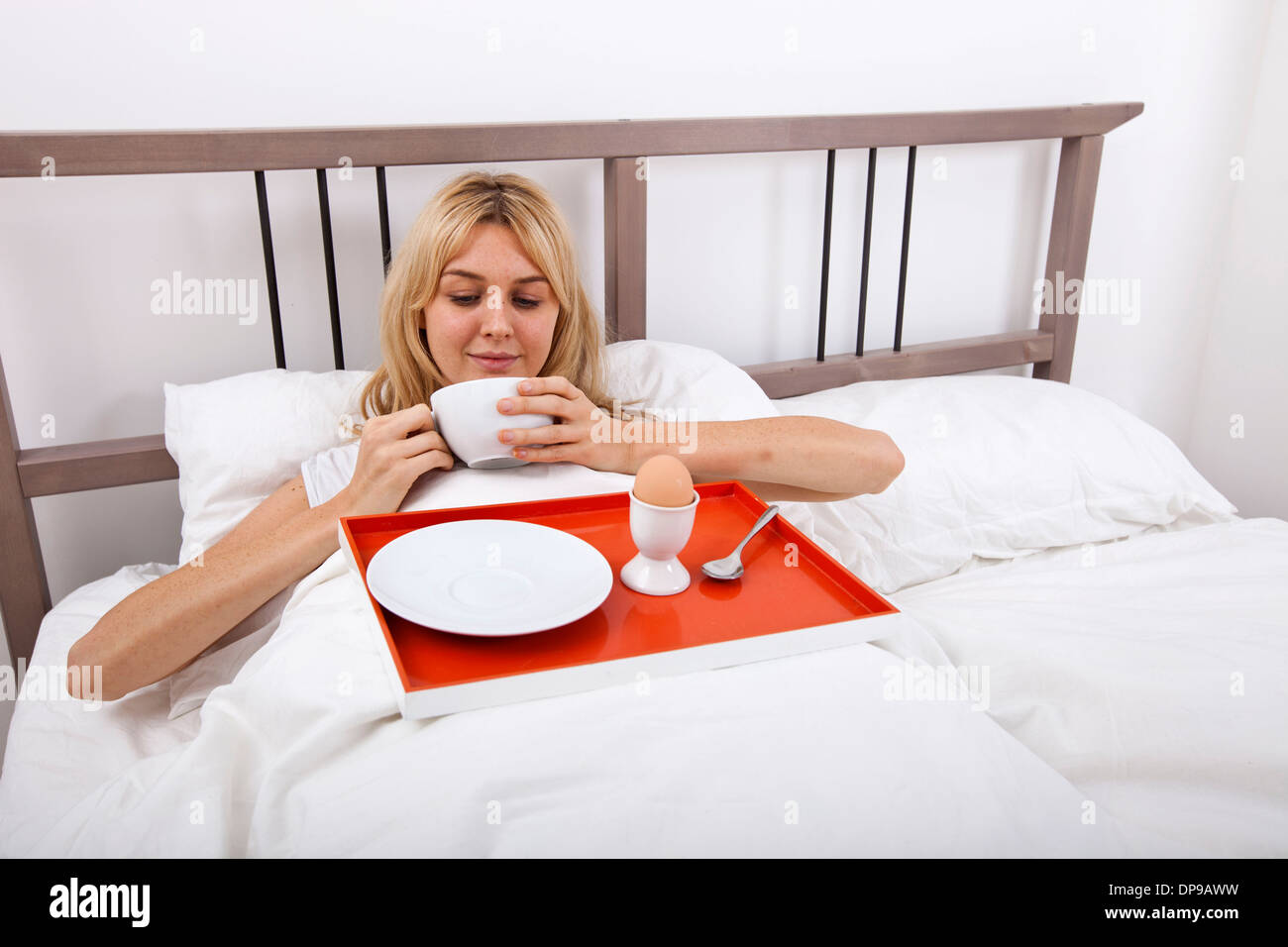 Junge Frau mit Frühstückstablett im Bett Stockfoto