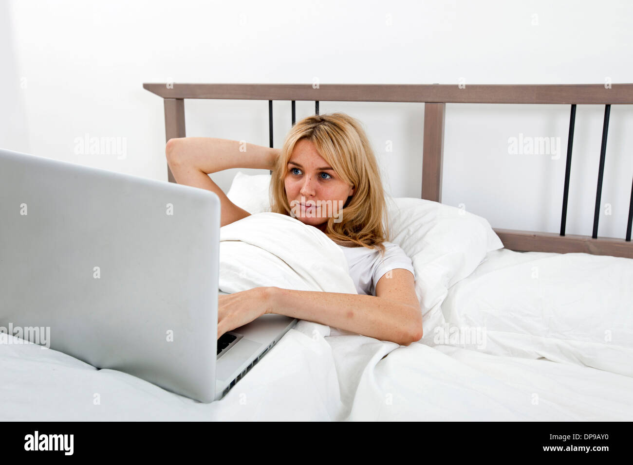 Junge Frau, die am Laptop im Bett Stockfoto