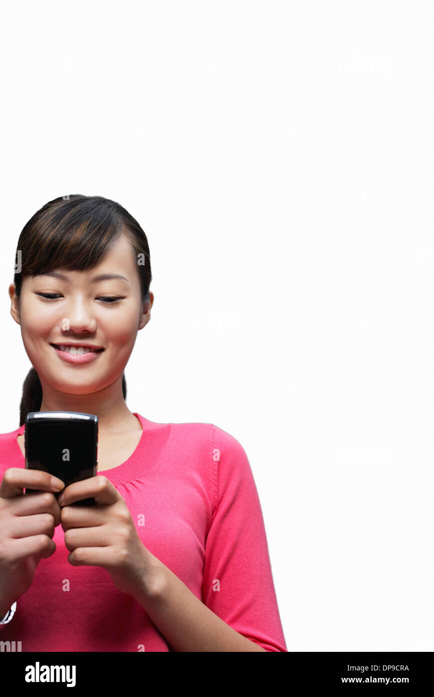 Junge Frau SMS auf Handy vor weißem Hintergrund Stockfoto