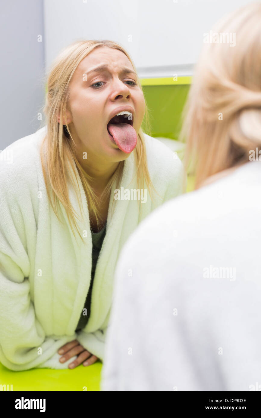 Junge Frau, die Untersuchung der Zunge im Spiegel Stockfoto