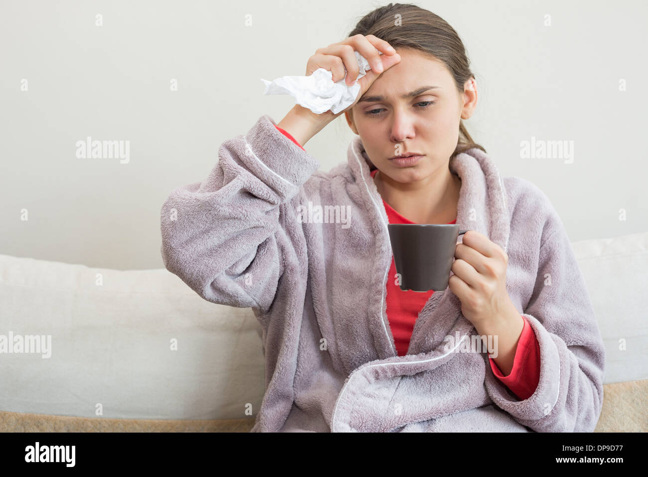 Junge Frau leidet Kälte Kaffeetrinken auf Bett Stockfoto