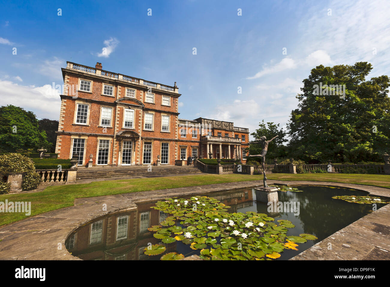 Großes Herrenhaus mit Landschaftsgärten, Teich und Skulptur. Stockfoto