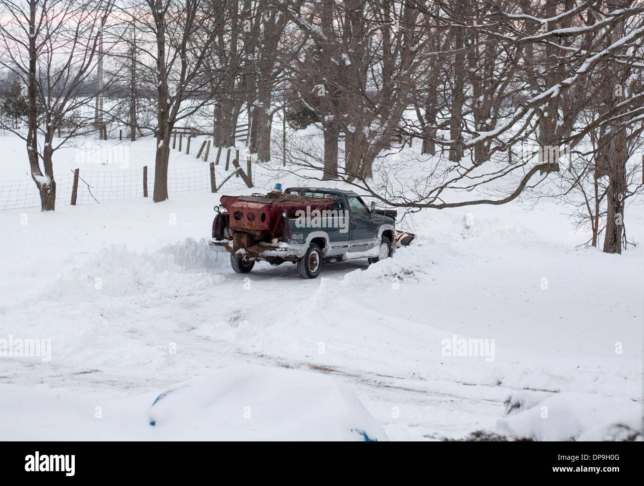4 x 4 LKW mit Schneepflug Aufräumen eine Hof-Einfahrt nach einem schweren Schneesturm. Sand in der Rückseite des LKW wird verwendet, um belasten Stockfoto