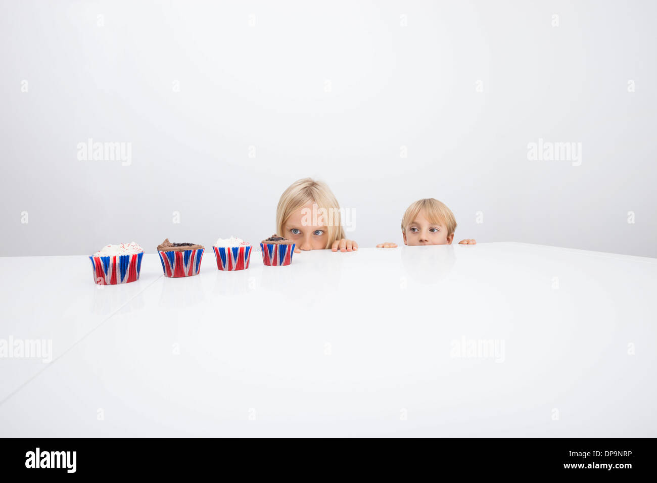 Versucht Kinder starren auf Cupcakes auf Tisch Stockfoto