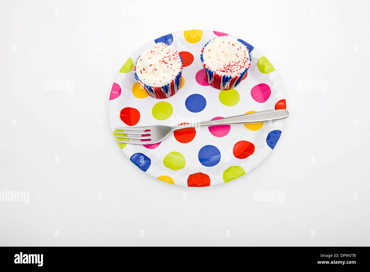 Erhöhte Ansicht von Cupcakes in bunten Teller vor weißem Hintergrund Stockfoto