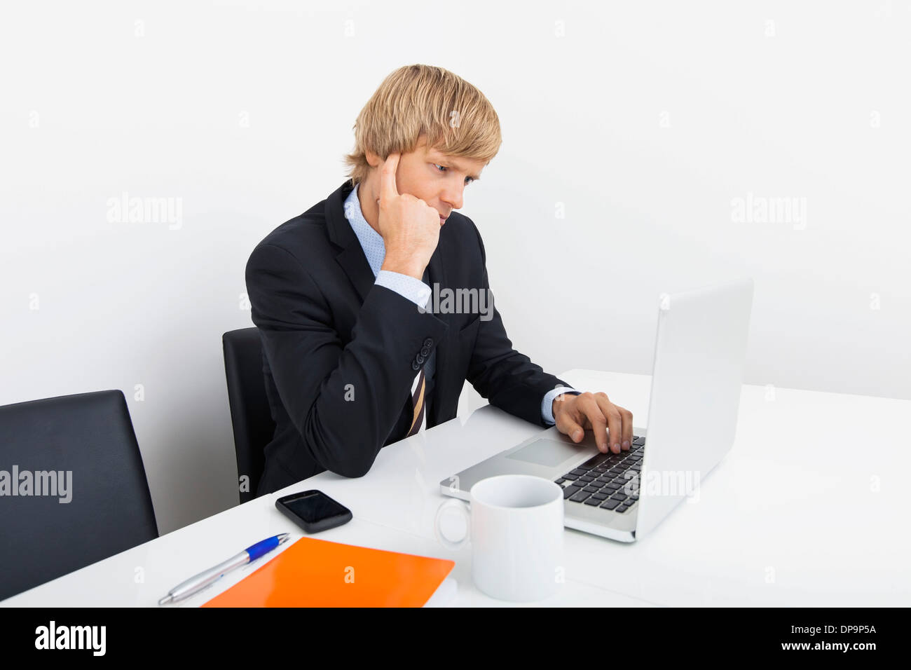 Geschäftsmann mit Laptop am Schreibtisch im Büro Stockfoto