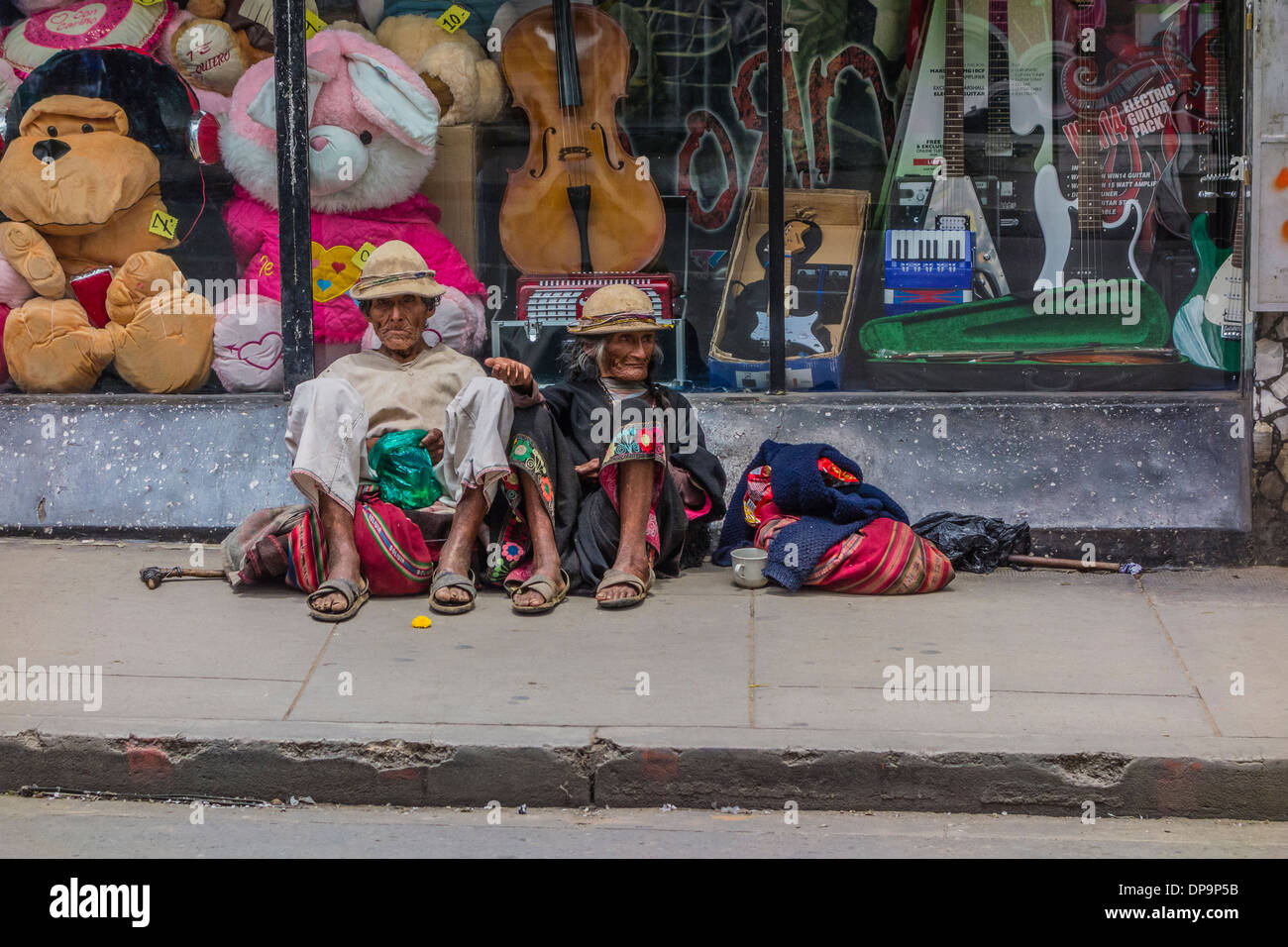 Indigenen Mann und Frau sitzend auf dem Bürgersteig vor einem Schaufenster in Sucre, Bolivien betteln. Stockfoto