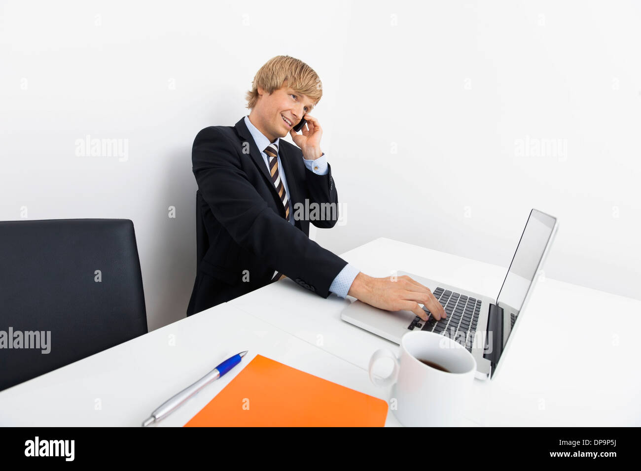 Zuversichtlich Geschäftsmann auf Abruf während mit Laptop am Schreibtisch im Büro Stockfoto