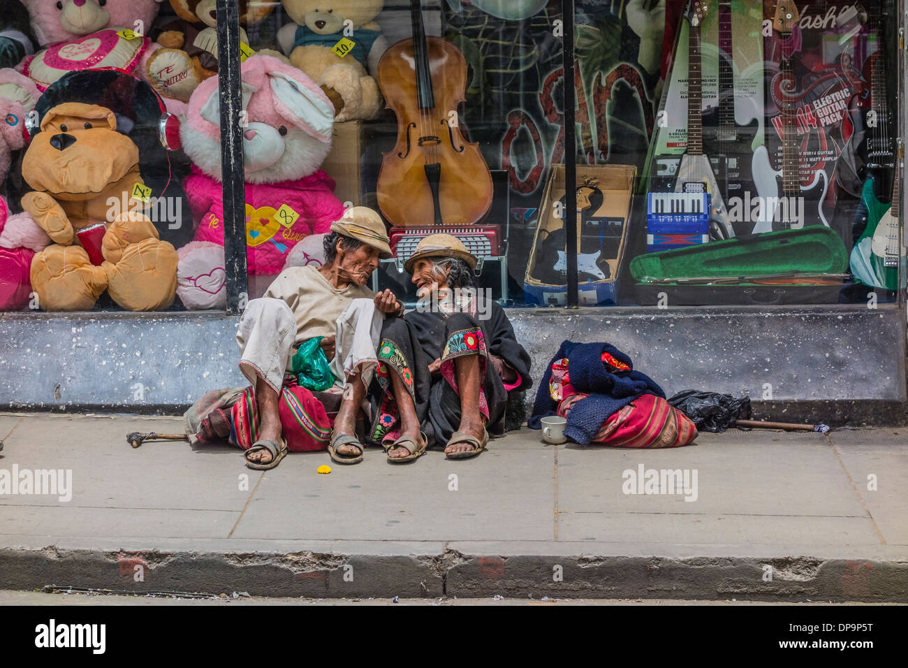 Indigenen Mann und Frau sitzend auf dem Bürgersteig vor einem Schaufenster in Sucre, Bolivien betteln. Stockfoto