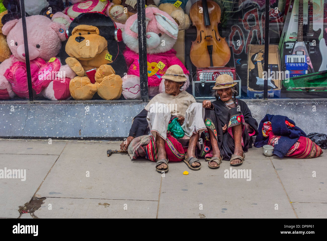 Indigenen Mann und Frau sitzend auf dem Bürgersteig vor einem Schaufenster in Sucre, Bolivien betteln. Stockfoto