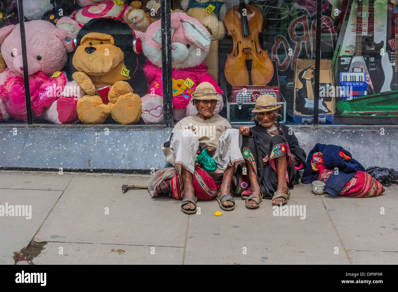 Indigenen Mann und Frau sitzend auf dem Bürgersteig vor einem Schaufenster in Sucre, Bolivien betteln. Stockfoto
