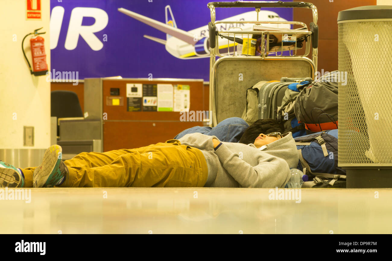 Personen, die am Ryanair-Check-in-Schalter im Flughafenterminal auf dem Boden schlafen. Stockfoto