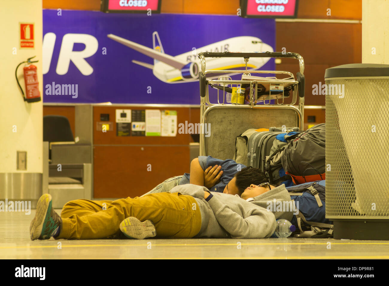 Personen, die am Ryanair-Check-in-Schalter im Flughafenterminal auf dem Boden schlafen. Stockfoto