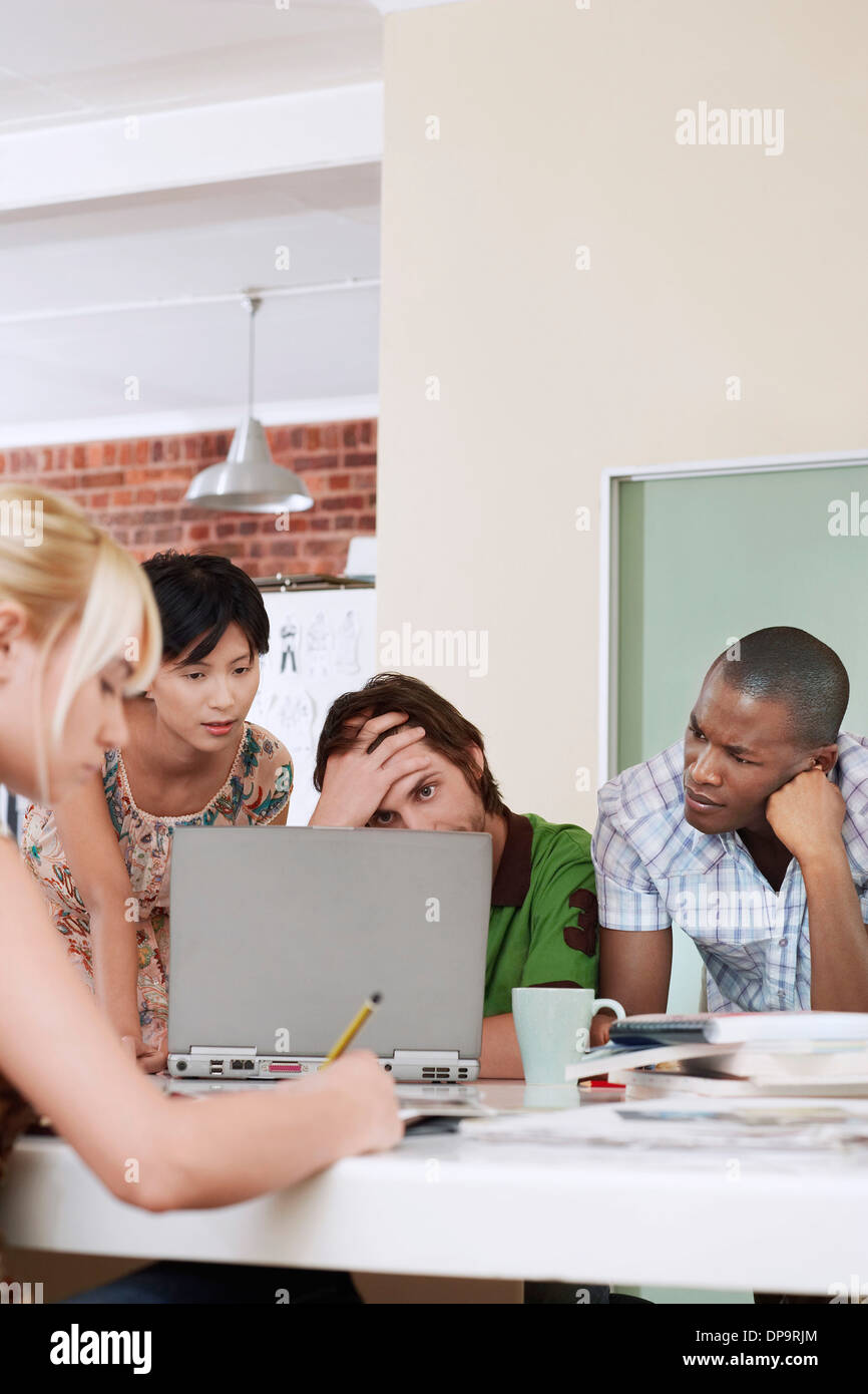 Vier Menschen treffen um einen Laptop. Stockfoto