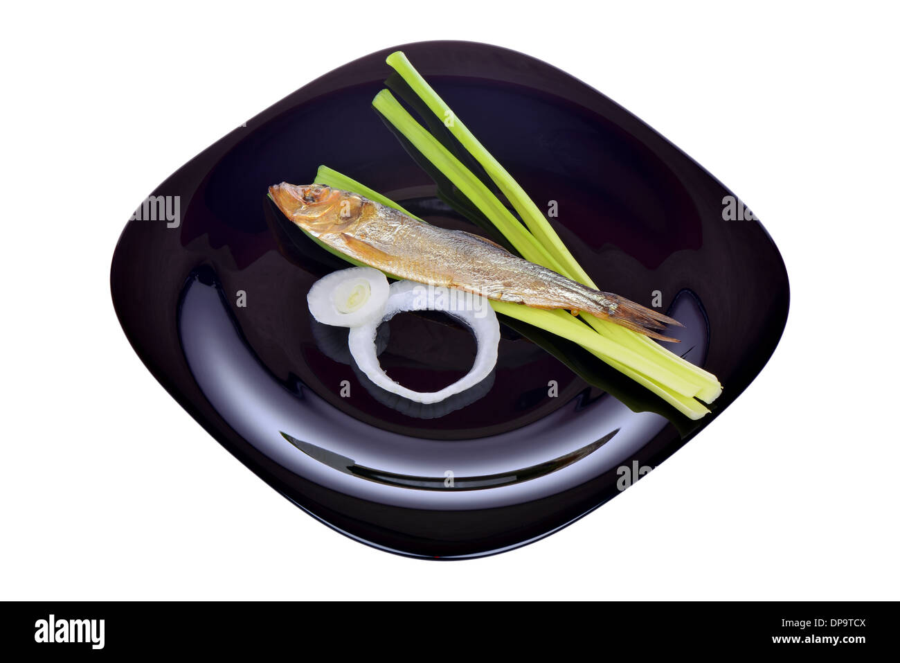 Geräucherter Fisch und Zwiebeln auf einem schwarzen Teller Stockfoto