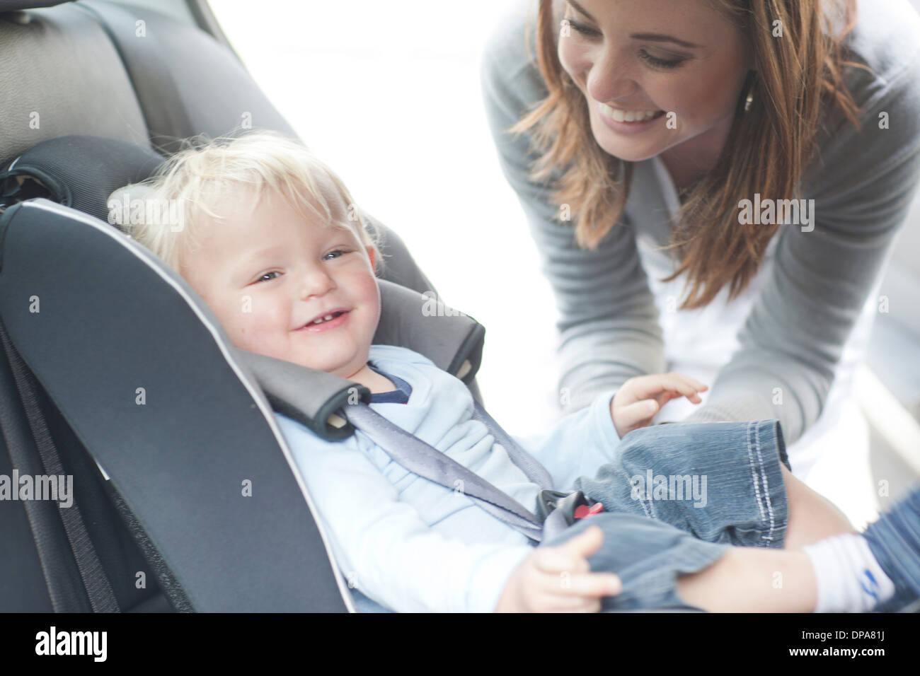 Mutter Überprüfung Baby Sohn im Rücksitz des Wagens Stockfoto