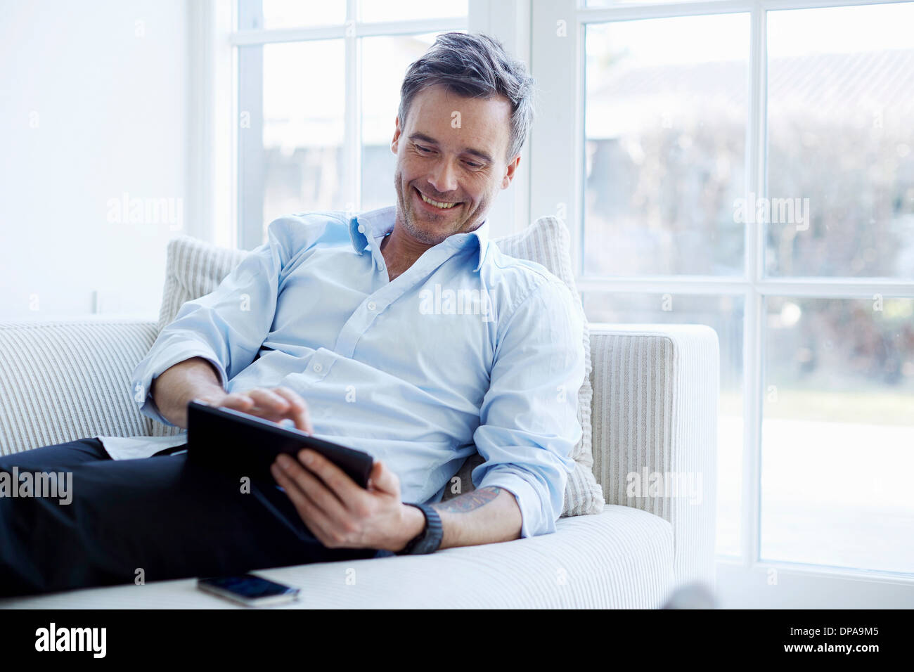 Mann auf Sofa mit digital-Tablette Stockfoto