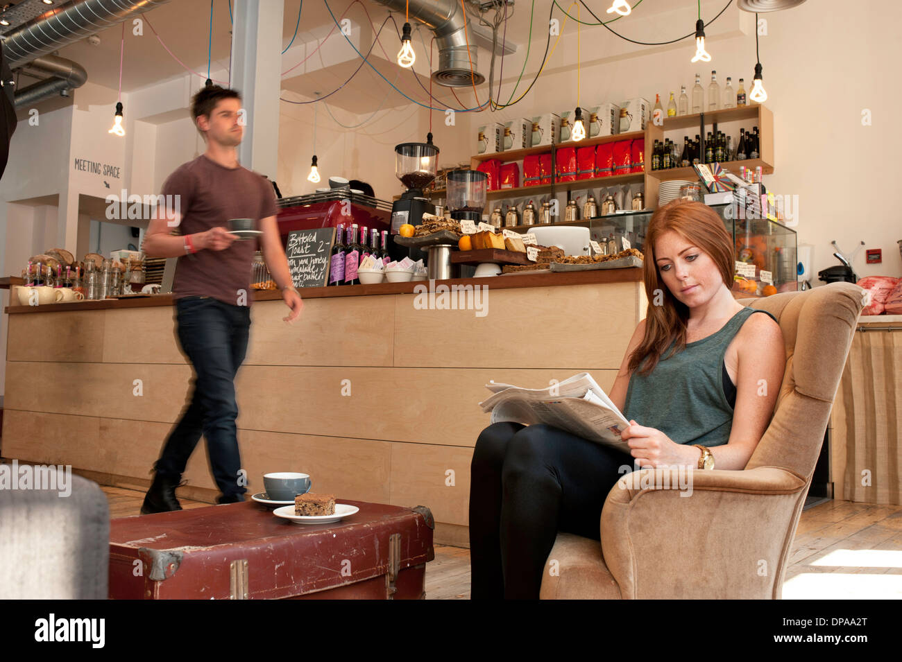 Junge Frau mit Tee und Zeitunglesen im café Stockfoto