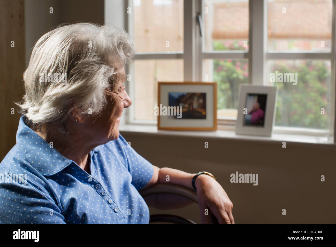 Ältere Erwachsene Frau im Zimmer Blick aus Fenster Stockfoto