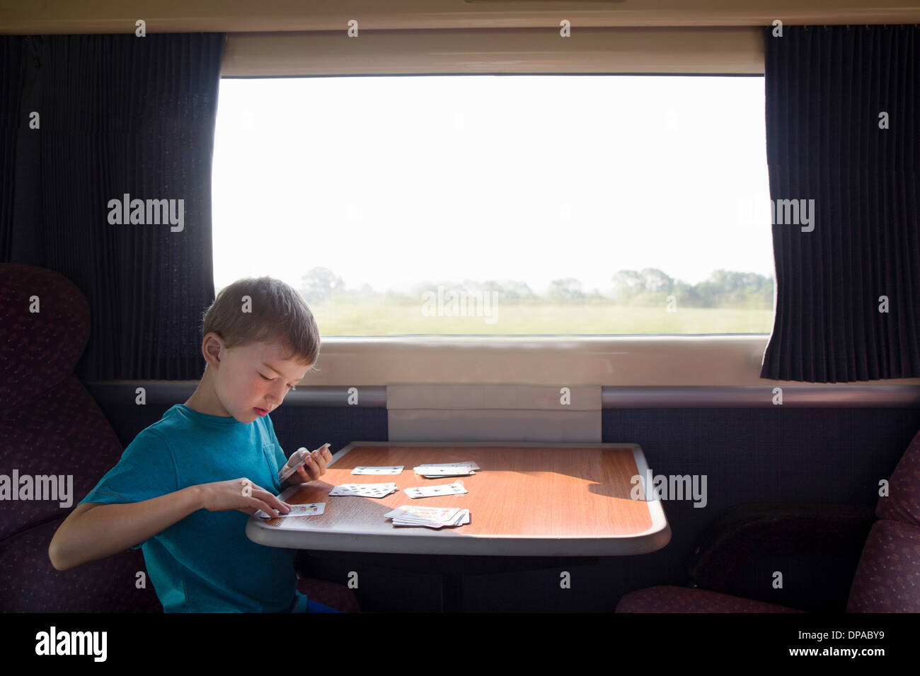 Junge mit Spielkarten auf Zug Stockfoto