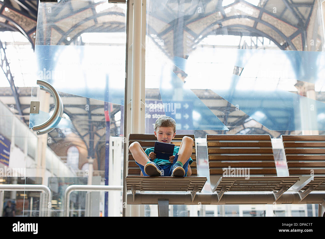 Kleiner Junge im Zug Bahnhof Wartezimmer Handheld-Spiel Stockfoto