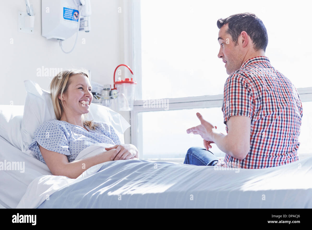 Patienten im Krankenhausbett im Gespräch mit Besucher Stockfoto